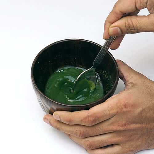 mixing matcha tea in water with spoon